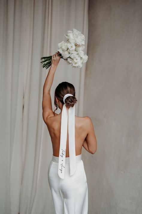 Bride with her back to teh camera wearing only a pair of bridal trousers and holding a bouquet above her head, also wears her hair tied back in a bun and secured with a long silk ribbon that has personalised embroidery on it. Wedding veil design by Rebecca Anne Designs. Bridal Hair Ribbon, Wedding Veil Styles, Veil Styles, Duchess Satin, Hair Ribbon, Bride Accessories, Embroidered Wedding, Wedding Ribbon, Bridal Hair And Makeup