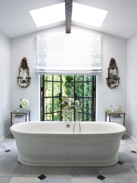 Elegant bathroom with light gray walls and freestanding stone bathtub. Carrara marble floor tiles with black diamond accent. Black iron and glass patio doors leading to balcony, flanked by antique mirrored wall sconces and glass and iron accent tables. Nate Berkus Design, Hollywood Hills Homes, Easy Home Improvement, Nate Berkus, Los Angeles Homes, Powder Rooms, Bath Tub, Bathtubs, Beautiful Bathrooms