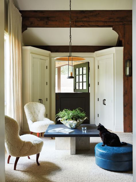 The family’s feline, Coco, perches atop a Lee Industries ottoman in Jerry Pair Leather’s Bella Pella in this family room sitting area. The Dutch door is painted Sherwin-Williams’ Black Fox. Rose Tarlow Melrose House’s Buttercup pendant illuminates wooly armchairs from Laserow and a low Clubcu cocktail table. Rose Tarlow Melrose House, Rose Tarlow, Mud Room Entry, Architecture Home, Luxurious Home, Southern Homes, Dutch Door, Luxe Interiors, Home Tours