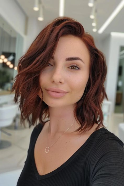 Woman with wavy auburn hair and a black top smiling in a bright salon. Solid Chocolate Brown Hair, Light Reddish Brown Hair Color, Natural Red Highlights, Light Reddish Brown Hair, Warm Chocolate Brown Hair, Mocha Balayage, Reddish Brown Hair Color, Dimensional Balayage, Chocolate Brown Hair Color Ideas