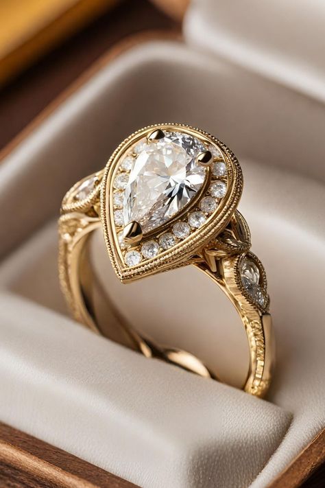 Delve into the charm of yesteryear with the Unique Vintage Halo Pear Diamond Engagement Ring, set in warm yellow gold and adorned with intricate milgrain detailing. This exquisite ring combines a pear-shaped diamond with a halo of smaller diamonds, exuding an air of sophistication and vintage elegance. Click to learn more about this stunning piece, prominently featured as number two in our list of 27 best pear engagement rings, and see how it captures the essence of antique glamour. Pear Shaped Vintage Rings, Art Deco Halo Engagement Ring, Unique Ring Designs Vintage, Vintage Rings Engagement Antiques, Vintage Gold Engagement Rings Antiques, Unique Engagement Rings Vintage Antiques, Unique Pear Engagement Ring, Vintage Pear Engagement Ring, Gold Pear Engagement Ring