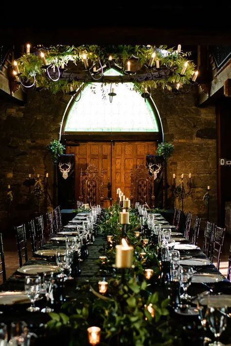 a LOTR wedding reception space indoors, with a black table with greenery and gold candles, a greenery chandelier with vines Elven Wedding Reception, Viking Wedding Table Centerpieces, Medieval Centerpieces Wedding, Celtic Woodland Wedding, Game Of Thrones Wedding Aesthetic, Midevil Wedding Theme Ideas, Fantasy Wedding Ceremony, Medieval Castle Wedding, Nordic Inspired Wedding