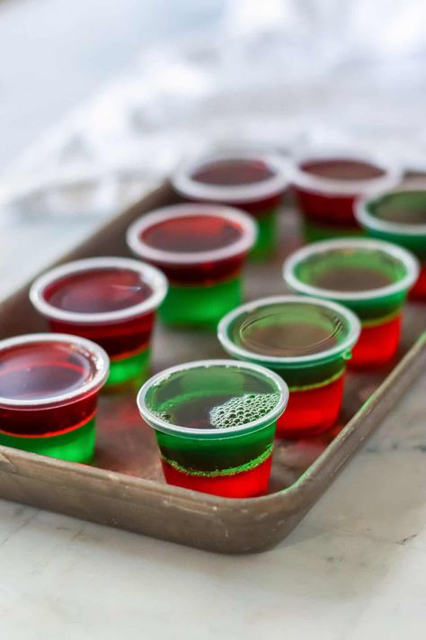 Christmas jello shots are the perfect boozy treat for the holiday season! Made with layers of red and green jello and topped with whipped cream and sprinkles, these festive jello shots are easy to make with just a few simple ingredients and perfect for holiday parties. Holiday Jello Shots, Christmas Jello Shots, Jell O Shots, Christmas Shots, Jelly Shots, Pudding Shots, Jello Shot Recipes, Jello Shot, Grinch Party