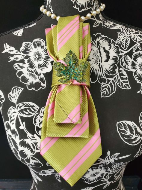 This Pink and Green Stripe Necktie Necklace is made with a (Barry Wang) woven silk tie, and features a Gold and Green Rhinestone Ivy Branch Brooch strung on your choice of an adjustable Rosary Chain Ribbon Tie Pearl Necklace or an adjustable Elastic Band. The soft, comfortable fabric sits perfectly on any size chest, while the adjustable necklace feature allows you to customize the fit to your liking. Measuring at a versatile length, this necktie necklace is designed to be a one-size-fits-all. V Pearl Tie Necklace, Neck Tie Necklace Diy, Necktie Necklace Diy, Necktie For Women, Diy Necktie Projects, Necktie Necklace, Dark Green Coat, Fancy Tie, Tie Brooch