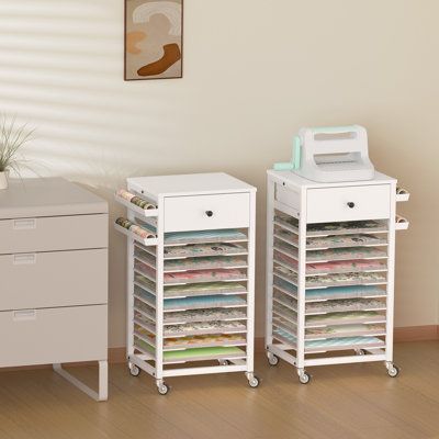 The multifunctional craft storage organizer consists of 10 layers of partitions, 1 drawer, and 2 metal baskets. Each tier can accommodate 150 pieces of 12" x 12" papers, with a total capacity of 1500 pieces across all 10 tiers. A large quantity capacity suitable for scrapbook storage enthusiasts and managers, practical for offices, bedrooms, classrooms, and handicraft classes. | Rebrilliant Marshana Rolling Craft Table 12 x 12 Paper Storage Cart for Craft Room Home Brown/White 27.3 x 14.0 x 12.6 Rolling Craft Table, 12 X 12 Paper Storage, Ikea Sewing Rooms, Storage Cart With Drawers, Scrapbook Room Organization, Craft Storage Cabinets, Craft Paper Storage, Crafting Table, Sewing Room Storage