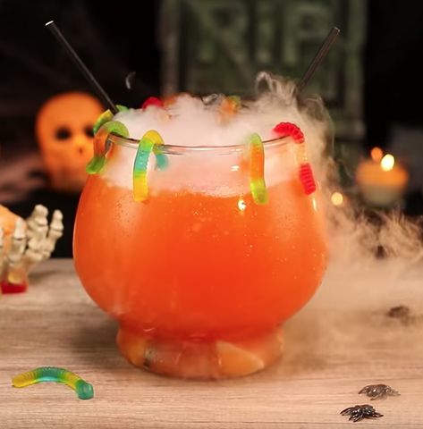 Ladies and gentlemen, here we have the Wicked Worm Punch, one of the wildest smoking Halloween drinks out there. This delicious orange Halloween punch mixes up vodka, Triple Sec, pineapple juice, orange soda, and a pint of orange sherbert, making it the ideal dessert punch for your Halloween parties. This awesome Halloween punch bowl is also garnished with gummy worms just to up those spooky dessert drink recipe vibes. Spooky Drinks Alcohol Halloween Punch, Spiked Halloween Punch, Orange Halloween Punch, Spooky Jungle Juice, Halloween Spiked Punch, Halloween Jungle Juice Recipe Alcoholic, Orange Halloween Drinks Alcohol, Jungle Juice Halloween, Halloween Drinks Alcohol Punch Bowl