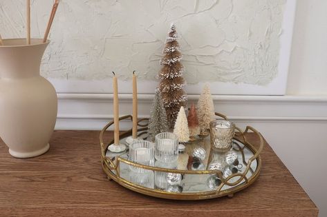 A mirrored tray makes a chic centerpiece when layered with reflective elements like mercury glass and glittered trees that really up the sparkle factor. It adds such a cozy feeling to your space— when you light the candles at night, the flames flicker and glow in the reflection of the mirror. Christmas Mirror Tray, Mirrored Tray Centerpiece, Candles At Night, Glass Tray Decor, Holiday Centerpieces Diy, Centerpiece Tutorial, Gold Mirror Tray, Mirror Centerpiece, Tray Centerpiece