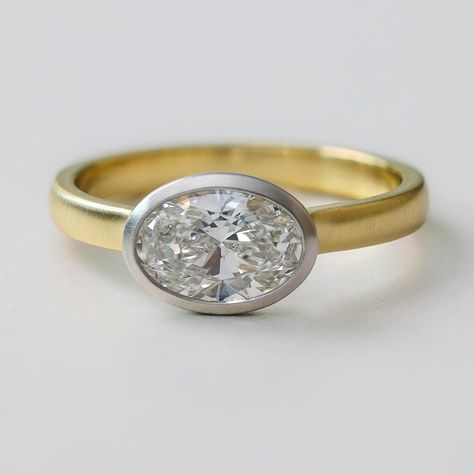 Introducing "Juni", a modern and minimalistic East-West Oval Diamond Engagement Ring. Expertly crafted in New York City, this low-set ring is designed for everyday wear without compromising on style. The oval diamond, set in a brushed two-tone metal bezel, exudes sophistication while the low-profile setting ensures practicality and comfort. Shown in the listing picture and video with 1 carat oval diamond. We can set this with any stone shape and size so contact us for a quote. If you want natura East West Bezel Engagement Ring, Low Profile Engagement Ring, Low Profile Engagement Rings, Bezel Engagement Ring, Oval Diamond Engagement, Oval Diamond Engagement Ring, Bezel Ring, Set Ring, Oval Cut Diamond