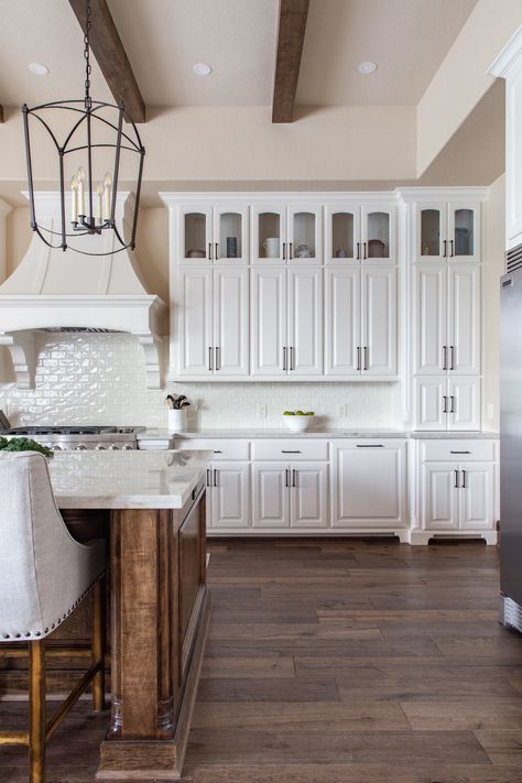 White Kitchen with Stained Island - Farmhouse Kitchen in White. The stained kitchen island is perfectly balanced by the soft, white kitchen cabinets in this custom kitchen. #FarmhouseKitchenInWhite #RusticWhiteKitchen #StainedKitchenIsland #CustomKitchenDesign White Cabinets With Stained Island, Wood Stained Island, White Kitchen Cabinets With Stained Wood Island, White Kitchen Stained Island, White Kitchen Cabinets With Wood Island, White Kitchen Brown Island, Stained Island White Cabinets, Stained Kitchen Island, Wood Island White Cabinets