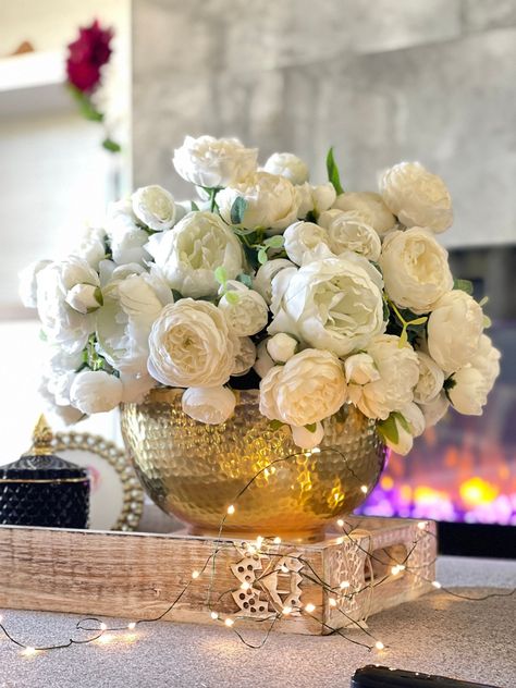 Opt for a simple, natural color palette with white, red, and wooden elements. White And Gold Artificial Flowers, Gold Vase Flower Arrangement, White And Gold Floral Centerpieces, Gold And White Centerpieces, Dinner Table Centerpiece Ideas, Gold Vase Flowers, Color Palette With White, Centerpieces Dining Table, Gold Tray Decor