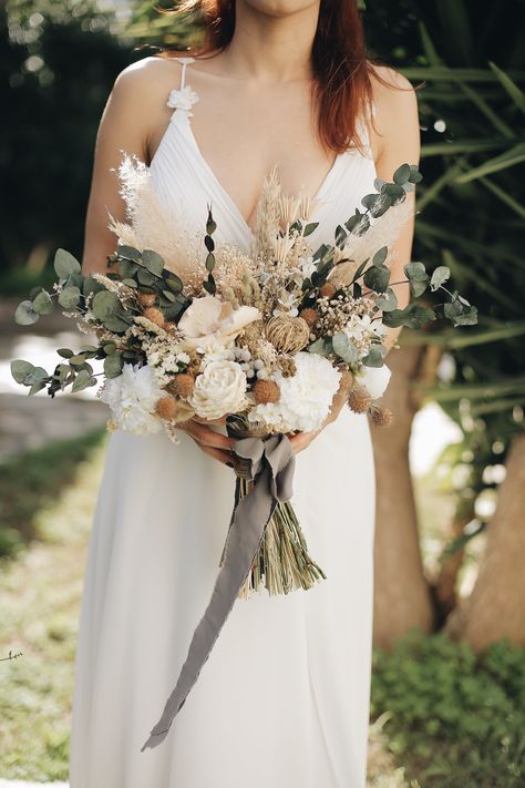 Preserved flowers are made up of flowers, nicolly leaves and real peonies with a high appearance. These flowers combined with the leaves of populus and nicolly, achieving an elegant image. White and green are among the favorite colors for many brides. It is an ideal bouquet for bride candidates who want an elegant, natural and romantic image.  Green and white were accompanied by natural earthy tones. Dried fruits collected from different trees from one to another added harmony to this bouquet.  It has a form that expands to the sides. While most wedding bouquet shapes tend to be more vertical in nature, freeform bouquets are often more horizontal, are loosely tied with gorgeous ribbon and often incorporate gorgeous greenery, a wide variety of flowers with varying stem lengths, and are perf Bridal Bouquet Gold And Green, Earthy Bride Bouquet, Winter Boho Wedding Flowers, Green And Champagne Wedding Flowers, Boho Bride Bouquet Wild Flowers, Contemporary Bridal Bouquet, Wedding Bouquets White And Green, Green Bride Bouquet, Green Dried Flower Bouquet