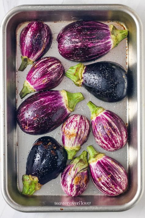 Oiled and seasoned mini eggplants on a small baking sheet. How To Roast Eggplant In Oven, Fairy Tail Eggplant Recipes, Small Eggplant Recipes Easy, Baby Eggplant Recipes Simple, Purple Eggplant Recipes, Graffiti Eggplant Recipes, Fairytale Eggplant Recipes, Eggplant Appetizer Recipes, Eggplant Recipes Easy Baked