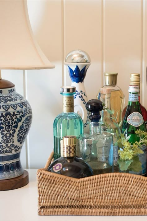 bar setup in rattan tray with blue & white ceramic lamp nearby. Home Bar Setup, Coastal Cottage Decorating, Home Bar Cabinet, Bar Setup, Southern Traditional, Home Bar Design, Bar Tray, Bar Cart Styling, Spring Refresh