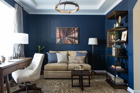 We transformed the formal dining into a masculine navy blue library and office area. We chose navy blue as the color for this masculine home office. We anchored the space with a traditional rug, rich gold accents, wood tones and this masculine leather strapped ottoman. We found a cream armless sofa that was the perfect scale for the room. #mancaveideas #mancavedecor #masculineoffice #homelibrary #masculinelivingroom #masculinedecor #manlyoffice #dwellbycheryl #armlesssofa #manofficedecorhome Home Office Sofa Layout, Navy Cream Gold Bedroom, Home Office Setup With Couch, Masculine Office Guest Room Combo, Home Office Navy Blue, Office With A Couch Ideas, Office And Lounge Combo, Masculine Blue Living Room, Office Room With Couch