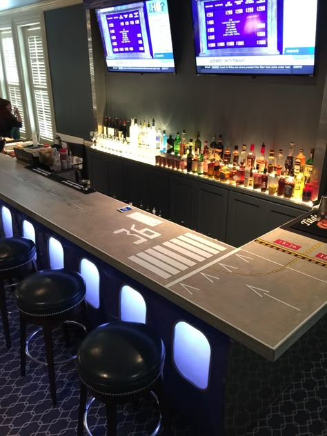 Airport themed bar with runway printed bar top. Aviation Bar Ideas, Airplane Hanger Man Cave, Aviation Themed Bar, Aviation Man Cave, Aviation Decor Interior Design, Aviation Bar, Military Bar, Aviation Office, Aircraft Furniture