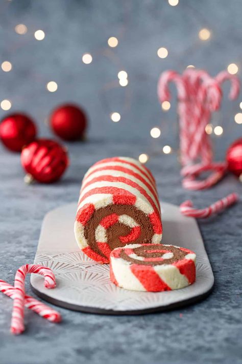 Red and white striped cake roll with one slice cut off to show a perfect spiral of chocolate peppermint whipped cream filling, with candy canes, red ornaments, and Christmas lights out of focus in the background. Peppermint Cake Roll, Candy Cane Cake, Peppermint Whipped Cream, Candy Cane Dessert, Peppermint Cake, Striped Cake, Peppermint Extract, Roll Cakes, Cake Roll Recipes