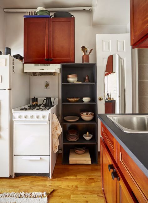 Small studio apartment kitchen corner with black storage shelf and petite stove Best Kitchen Storage, Nyc Studio Apartments, Tiny Studio Apartments, Simple Bookshelf, Linen Bed Cover, Furniture Apartment, Apartment In New York, Kitchen Addition, Nyc Studio