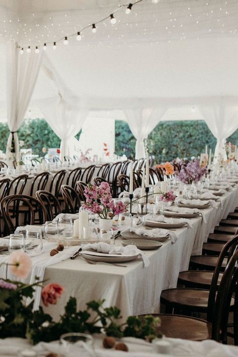 styling of a white wedding reception tent with long table rows, brown bentwood chairs, oatmeal tablecloths, white napkins, taper and pillar candles, menus, cutlery and floral arrangements Black Taper Candle Holders, Styling Candles, Spring Wedding Reception, Floral Centrepieces, Romantic Spring Wedding, Black Taper Candles, Silver Cutlery, Bridal Table, White Napkins