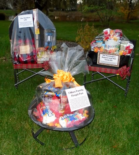 A camper's delight!  This was one gift - yes! - that featured two large-and-loaded sportsmen's chairs and a full fire pit!  There's a jumbo popcorn   gift on one of the chairs, the fire pit is full of all the fixin's for s'mores and the second chair features accessories for camping (blanket, lantern, etc). Camping Basket Ideas, Campfire Raffle Basket Ideas, Huge Gift Basket Ideas, Fire Pit Basket Ideas, Camping Raffle Basket Ideas, Large Gift Basket Ideas, Fire Pit Raffle Basket Ideas, Camping Auction Basket Ideas, Fire Pit Gift Basket Ideas