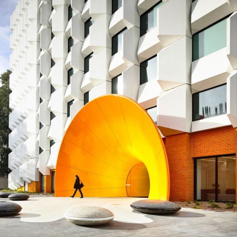 Conceived as a ‘curtain’, the new façade hangs from above and is lifted at various points along the ground plane to allow a glimpse behind of an array of custom coloured glazed bricks at the pedestrian level. Entry into the building is through a portal designed in collaboration with the artist Callum Morton. Curving in two directions, it draws on the artefacts of scientific research processes to provide passage to a ground floor gallery showing part of the extensive Monash University art collect Glazed Bricks, Underground Museum, Curve Building, Circular Buildings, Portal Design, Retail Facade, Round Building, Small Cafe Design, Modern Entry