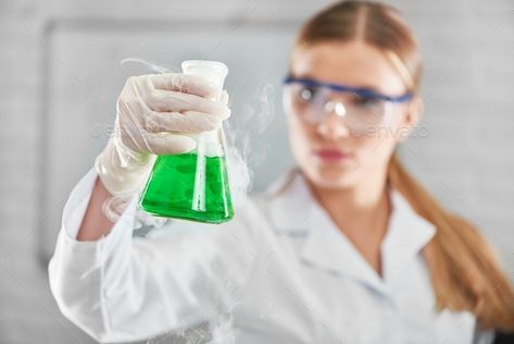 Female chemist working at the laboratory by serhiibobyk. Selective focus on a flask with green smoking chemical liquid in the hand of a young female researcher at the laborat... #Sponsored #Selective, #serhiibobyk, #flask, #focus Female Chemist, Female Scientist, Tech Outfit, Physical And Chemical Properties, Women Scientists, Brochure Template Layout, Research Scientist, Medical Doctor, Medical Laboratory