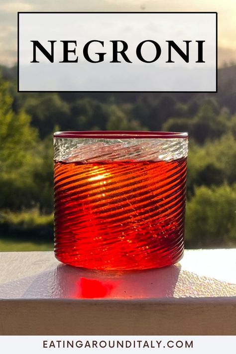 side view close up of a negroni on a wooden board outdoors at sunset with green in background with text box overlay Negroni Bottle, Smoked Negroni Cocktail, Negroni Sbagliato Cocktail, Negroni Sbagliato Cocktail Recipes, Negroni Sbagliato, Italian Cocktails, How To Pronounce, Negroni, Alcohol Drink Recipes