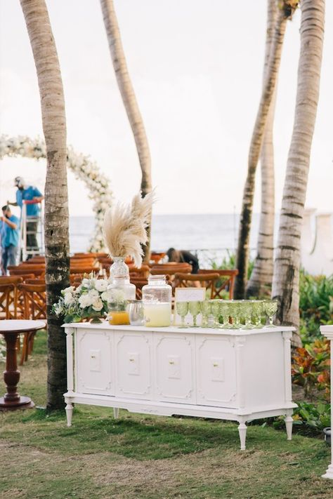 White credenza with aguas frescas, green glass. Cocktail hour. Beach wedding Belize Wedding, White Credenza, Cocktail Hour Wedding, Welcome Drink, Agua Fresca, Wedding Drink, Wedding Cocktails, Cocktail Hour, Belize