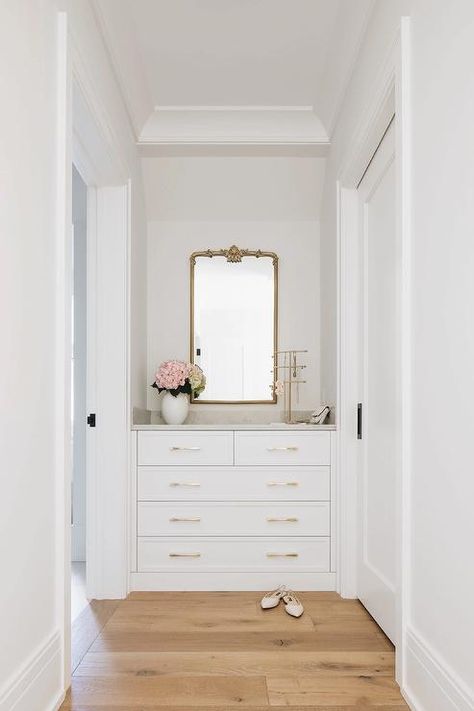 A closet nook is fitted with a white bulit-in dresser donning brass pulls and positioned under a gilt mirror. Nook In Bedroom, Tall White Dresser, Closet Nook, Transitional Closet, Closet Master, French Dresser, Storage For Clothes, Storage Vanity, Built In Dresser