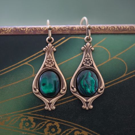 These charming Victorian floral drop earrings feature 10x8mm semi-precious mineral stone cabochons set in beautifully detailed settings. The earrings measure 28x13mm and dangle gracefully. Choose your favorite stone and select from oxidized brass or sterling silver, nickel-free wire hooks. These vintage-inspired earrings add a touch of classic elegance to any outfit. Explore our catalog of matching stone jewelry! Drawing Jewellery, Historical Hairstyles, Princess Vintage, Earrings Cuff, Aesthetic Jewellery, Crystals Earrings, Victorian Paintings, Green Characters, Sweet Accessories