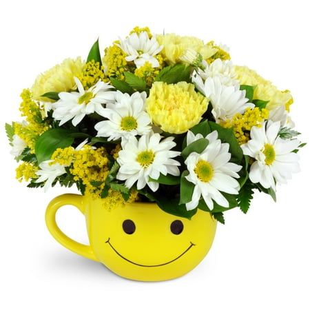 Nothing turns a frown upside down like this fun-filled mug. Send a sunny smile and bring joy to their day with this cheerful arrangement. Yellow carnations, white daisies, and solidago are arranged in a smiley-face mug to create the perfect pick-me-up. Size: premium.