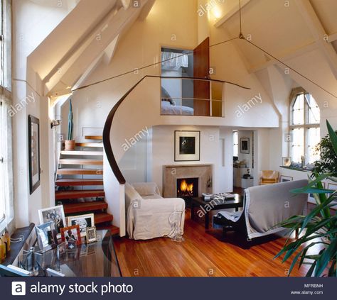 Spacious, split-level church conversion with wood floor, slip-covered couches, lit fireplace, and curving stairway to loft bedroom Stock Photo - Alamy Converted Homes, Loft Conversion Ideas, Chapel Conversion, Converted Church, Warehouse Loft, Church Conversions, Modern Outdoor Living, Church House, Loft Conversions