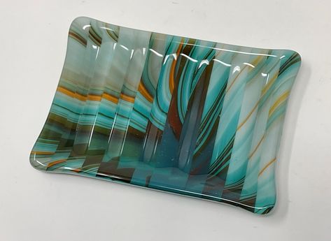 Beautiful southwest shades of turquoise, orange, brown and ivory art glass was cut into strips and rearranged to make this fused glass soap dish or sponge holder. It will be a one of a kind addition to your kitchen, bath or powder room decor. This art glass soap dish measures 3 5/8" wide and 5 1/4" long and will fit soaps of just about any size. Subtle formed ridges in the bottom of the dish help to circulate air beneath the soap or sponge holder and keep them dry between uses. A beautiful and functional piece to enhance your décor, as well as a perfect hostess or housewarming gift! Handmade in my home studio in North Carolina.  Thank you for taking the time to visit my shop! For more handmade glass items, please click here:  http://www.etsy.com/shop/angelasartglass Fused Glass Soap Dish, Fused Glass Trinket Dish, Soap Dish Ideas, Fused Glass Bowls, Fused Plates, Fused Glass Plates Bowls, Fused Glass Dishes, Fused Glass Bowl, Fused Glass Plates