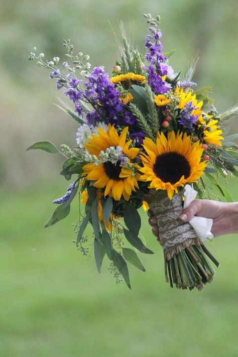 a bold wedding bouquet made of sunflowers, purple and white blooms and much greenery and wheat Western Wedding Sunflowers, Sunflowers And Lilacs, Purple Black Sunflower Wedding, Wheat And Eucalyptus Bouquet, Sage Green Bridesmaid Dresses With Sunflower Bouquet, Wedding Dress Sunflower, Sunflowers Bouquet Wedding, Sunflower And Lilac Bouquet, Sunflower Pampas Bouquet