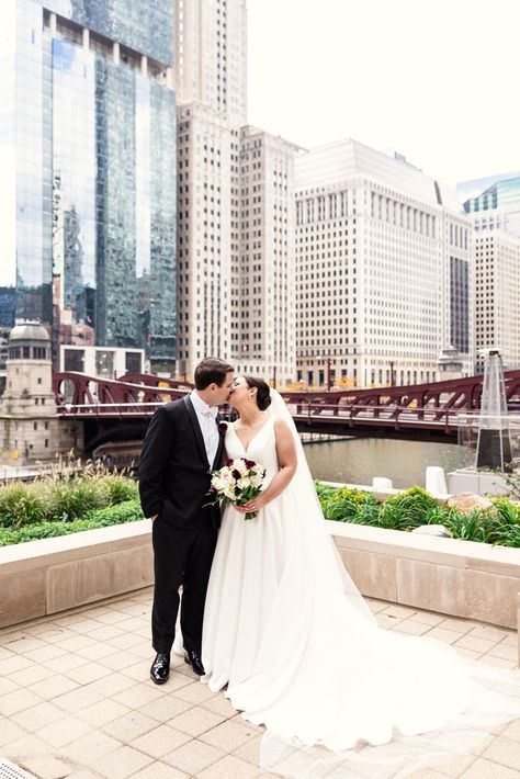 Bride and groom kiss near the river outside the Westin River North with downtown Chicago buildings in the background Bride And Groom Kiss, Chicago Fall, Fall Wedding Reception, Chicago Buildings, Autumn Wedding Reception, Wedding Traditions, Chicago Wedding Venues, St Benedict, New Orleans Wedding