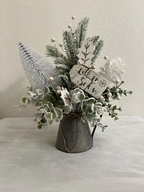 Wouldn't this beautiful rustic "Let It Snow", Christmas Tree arrangement and pine cone table decoration in small watering pitcher for your country, farmhouse winter, holiday, or Christmas season in your lovely home.  In this small floral arrangement I have added flocked artificial pine, spruce, greenery, white berries, frosted eucalyptus in a galvanized watering can centerpiece with brown twine bow that I added.  This floral arrangement can go from kitchen to your beautiful bedroom to your living room to your bathroom and through out the rest of your beautiful home with ease.  This would also make a great gift for a hostess, a friend or family member unable to come home for the holiday, use as a centerpiece for a party, wedding, birthday, or anniversary party. (Placement and look of greene Fake Christmas Flower Arrangements, Pinecone Centerpiece Christmas, Small Winter Floral Arrangements, January Table Centerpieces, Small Christmas Floral Arrangements, Decorating With Eucalyptus, Christmas Vase Arrangements, Watering Can Centerpieces, Winter Vase