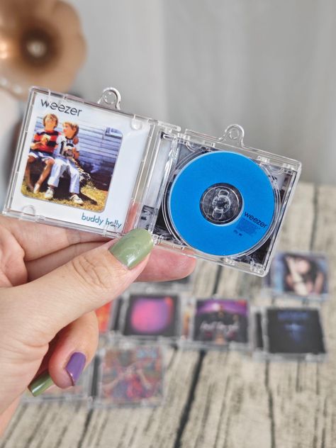 🎶 Custom Mini Album CD Keychain with NFC - Play Your Favorite Spotify Song Anytime, Anywhere! 🎧 Introducing the perfect gift for music lovers! Our Mini Album CD Keychain is more than just a cool accessory--it's a tiny portal to your favorite song. With an embedded NFC chip, simply tap your keychain against your phone, and your chosen song will start playing on Spotify instantly! 📱🎵 How It Works: - Choose Your Song: Copy the Spotify share-link of the song you want on your keychain. 🎶🔗 - Specify Artist & Album: Provide the name of the artist and the album the song is from, and we'll recreate the miniature album cover in stunning detail. 🎨✨ - Get Your Custom Keychain: We'll embed the song into your personalized mini album CD keychain and ship it directly to you! 📦💌 Why You'll Love It Cd Keychain, Music Items, Artist Album, Favorite Song, Cd Album, Gift For Music Lover, Played Yourself, Music Gifts, Personalized Keychain