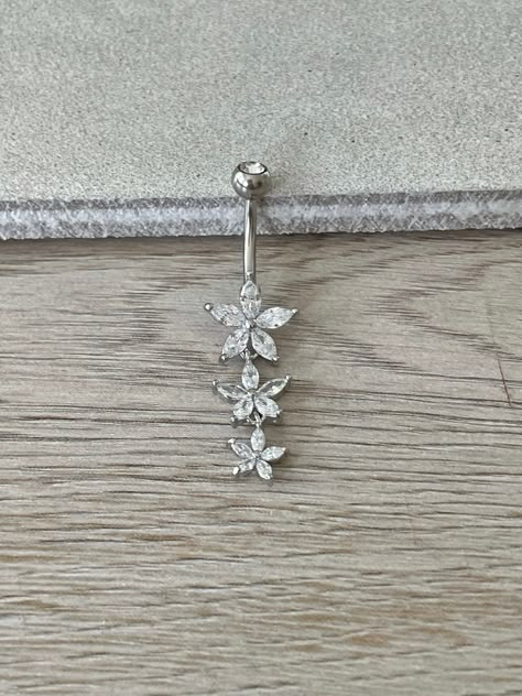 This silver surgical steel belly button ring features three flowers with cubic zirconia crystals in a drop design. A unique design, this floral belly ring is a great minimalist/delicate option. Drop jaws with this body jewelry. Details & Size: ♥ Surgical Steel ♥ Nickel Free ♥ Bar Length: 10mm, 14G ♥ Every purchase comes with an Elara gift box Please message me if you have any questions We hope you love our jewelry as much as we do! Dainty Belly Button Rings, Silver Belly Ring, Belly Button Piercing Silver, Silver Belly Piercing, Summer Belly Button Rings, Silver Belly Button Piercing, Dangle Belly Button Piercing, Unique Belly Rings, Cute Belly Rings