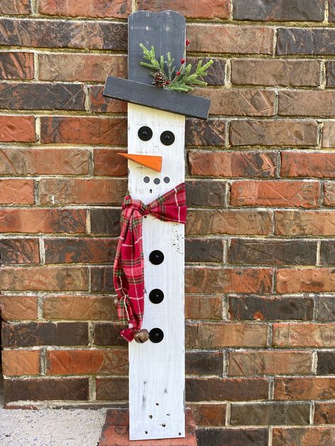 "These wooden snowmen yard or porch decorations are made using reclaimed pallet wood, painted white with a white wash effect. Scarf is fabric and will rival over time to add to the rustic effect.  The snowman has a red checkered scarf, with rustic jingle bells on the ends.  These snowmen can be propped up or be purchased with hardware to set in your yard. That would include the metal brackets as well as the metal post. These are sold separately but can be purchased as a set. Measurements: 34.5\"x5\" snowman 34\"x5.5\" snowwomen These are individuals and can be placed close to each other or apart. Due to the nature of using reclaimed wood, we can not guarantee each snowman will look the same as the picture. We will do our best to ensure that they match.  More in our shop: Decorative tray: h Christmas Decor Pallet Wood, Fence Post Snowman, Reversible Scarecrow Snowman, Diy Wooden Porch Signs, Pallet Board Crafts, Wooden Snowman Crafts Wood Patterns, Wooden Snowman Diy, Crafts With Bricks, Front Porch Diy Ideas