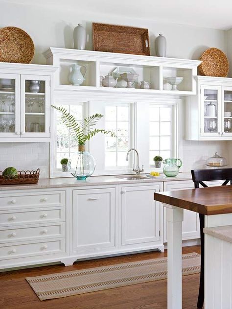 Window Dressing  A kitchen with windows offers an opportunity to incorporate storage in unexpected ways. In this kitchen, a bank of sturdy shelves has been installed directly over the window trim and painted the same crisp white as the trim and surrounding cabinetry. The fixed shelving adds display space for decorative dishware and draws attention to the stunning bank of windows. Kitchen With White Cabinets, Decorating Above Kitchen Cabinets, Above Cabinets, Above Kitchen Cabinets, Kabinet Dapur, New Kitchen Ideas, Kitchen Cabinets Decor, White Kitchens, Dream Kitchens