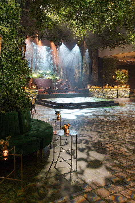 Immersive forest-like stage setup with spotlights and ambient greenery for a natural, mystical vibe. Enchanted Forest Event, Event Space Design, Nature Inspired Lighting, Family Mansion, Moody Lighting, Beneath The Stars, Jazz Lounge, Private Event Space, House Warming Invitations