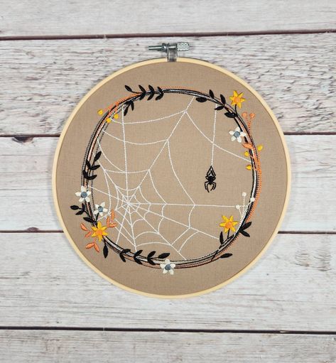 This spooky design of a spider with web surrounded by a wreath of flowers and leaves is machine embroidered and displayed in an 8" diameter bamboo hoop.  This hoop art would look nice hung up on the wall or just propped on a shelf and would compliment any decor.   Design is machine embroidered in shades of orange, white, yellow, black and gray thread on brown cotton fabric Fabric is stretched and tightened in the bamboo hoop and then trimmed and glued to inner frame to help prevent the fabric fr Diy Embroidery Flowers, Hoop Decor, Embroidery Hoop Decor, Embroidery Halloween, Brown Cotton Fabric, Fall Embroidery, Hoop Embroidery, Halloween Embroidery, Hand Embroidery Projects