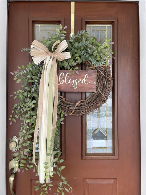 This artificial wreath can be displayed for all year round for an eye catching look. Treat yourself or gift for a birthday, housewarming or bridal shower.  My wreaths are made using only high quality artificial materials.  This design begins with an 18 inch natural grapevine base, however the completed look measures approximately 23 inches wide, 35 inches in height, and is about 6 inches deep.   The faux greenery, which creates interest and dimension, includes  eucalyptus branches and green smilax leaves with a hint of pink edges.  The ivory, sage green, and natural bow adds a touch of charm. The wood sign is stained mahogany, painted with antique white, and sealed for protection. Choose blessed, welcome, or hello at checkout.  I would recommend hanging under a covered porch or indoors for Green Diy Decor, Neutral Farmhouse, Farmhouse Style Wreath, Scranton Pa, Indoor Wreath, Eucalyptus Branches, Diy Balloon Decorations, Year Round Wreath, Artificial Wreath