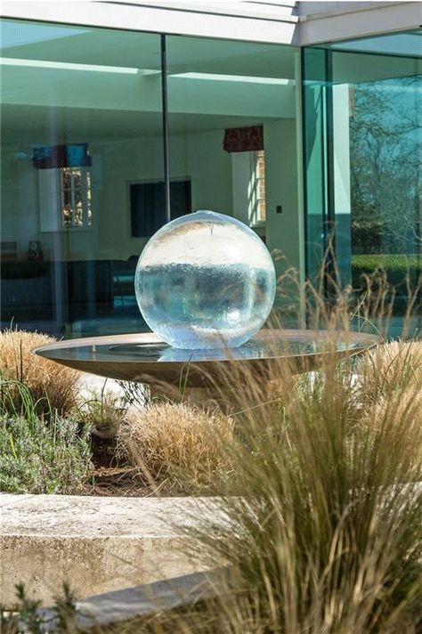 This classic Georgian farmhouse in West Sussex has been redesigned with modern additions. The Aqualens sits in the courtyard in front of the glass corridor, adding the perfect touch of modernity and luxury. Order yours today: allisonarmour.com #gardenfountain #gardenwaterfeature #modernfountain #luxuryfountain #modernhouse #modernstyle #farmhouse #modernfarmhouse #westsussex #landscapedesign #gardendesign #gardenart Circle Water Feature, Circular Water Feature, Spherical Water Feature, Sculptural Water Feature, Sphere Water Feature, Aqualens Sphere Fountain, Mid Century Modern Garden, Water Fountain Design, Modern Fountain