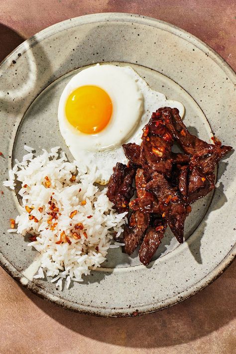 Tapsilog, a popular Filipino meal, is a portmanteau of the dish’s three components: tapa (beef), sinangag (garlic fried rice), and itlog (fried egg). It’s one of many variations of silog (garlic fried rice plus fried egg). While this recipe is fairly straightforward, we'll also tell you a few ways to ensure a great result. Though silog is traditionally served for breakfast, it makes a savory, satisfying meal any time of day. Tapsilog Recipe, Silog Meals Ideas, Silog Meals, Garlic Fried Rice, Cooking Jasmine Rice, Meals Ideas, Garlic Fries, Bulgogi, Satisfying Food