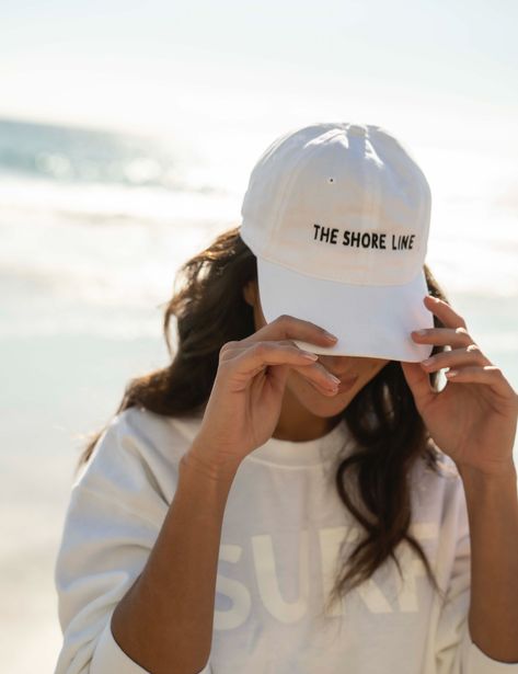 The logo baseball hat is a cotton hat that features an adjustable back strap. The embroidered THE SHORE LINE logo in contrast stitching sits at the center front. Size - one size fits most Beach Merch Photoshoot, Photos With Hats, Hat Product Photography, Hat Photoshoot Ideas, Merch Photoshoot Ideas, Hat Ads, Hat Modeling, Clothing Poses, Hat Poses