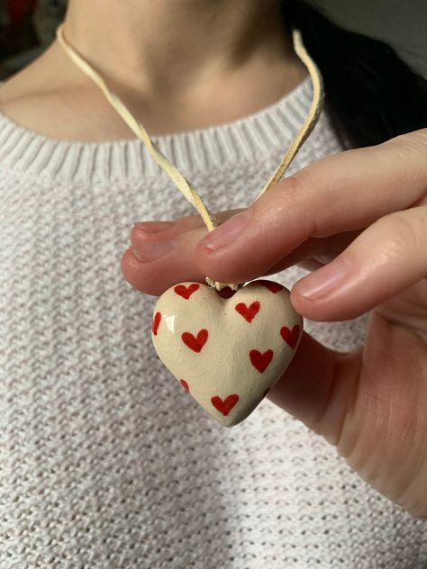 "💖   Ceramic Heart Pendant in White Clay, Necklace with Small Red Hearts 🌹🤍 Express your love with our exquisite Ceramic Heart Pendant, crafted from pure white clay and adorned with small, vibrant red hearts. This pendant is not just an accessory; it's a wearable declaration of love, perfect for lovers, mothers, or anyone who cherishes the symbol of affection. 🌟❤️ 🎨 Artisan-Crafted Romance: Meticulously handcrafted, this beige ceramic pendant is a testament to the artistry of clay craftsman Clay Heart Ideas, Handmade Clay Gifts, Handmade White Heart Pendant Charm Necklace, Clay Heart Necklace, Heart Eye Necklace Clay, Ceramic Heart Necklace, Clay Necklace Pendant, Ceramic Heart Pendant, Handmade Heart-shaped Red Necklaces