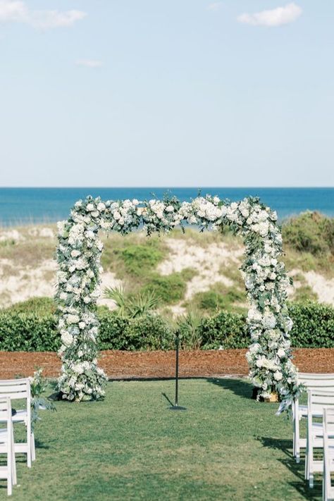 Floral archway with white flowers and greenery, creating a romantic and serene backdrop for a coastal wedding ceremony. White Rose Arch, Coastal Ceremony, Rose Arch, Floral Archway, Beachside Wedding, Palmetto Bluff, Romantic Wedding Decor, Coastal Wedding, Sea Island