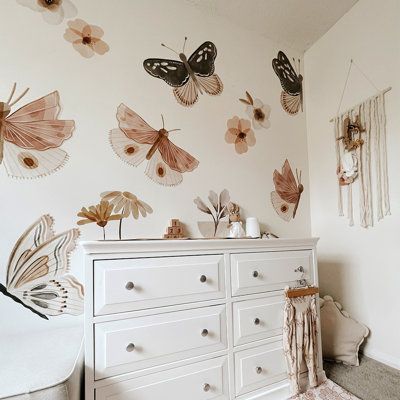 Whimsical and warm, the Butterfly Wall Decals from Urbanwalls deliver natural charm to any space. Created from toasted neutral tones, the decal pack features a variety of flowers and foliage with three variations of delicate butterflies. Gracie Oaks | Gracie Oaks Wall Decal black / whiteVinyl in Pink | 50" H X 50" W | Wayfair | Home Decor Lily Pad Nursery Theme, Gold And Pink Nursery Decor, Boho Nursery Wall Decals, Boho Butterfly Bedroom, Vintage Gothic Nursery, Flower And Butterfly Nursery, Floral Theme Nursery, Butterfly Garden Nursery, Toddler Butterfly Room