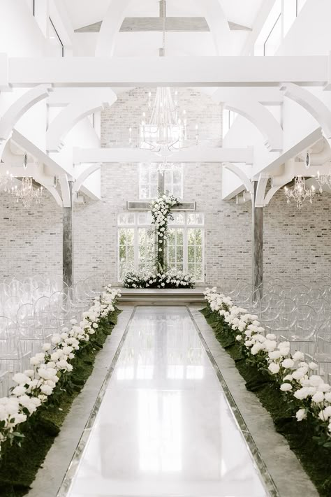 A modern and elegant wedding ceremony with all white florals and accenting greenery installed on and placed in front of the alter cross and long stemmed white roses lining the aisle as if growing up from the ground | Florals: Cali & Bloom, Venue: The Peach Orchard, Planning: Jolie Planning and Design, Photography: Erika Geier Photography Cross Aisle Wedding, White Cross Wedding Alter, White Roses Wedding Ceremony, The Peach Orchard Wedding, White Rose Aisle Wedding, Cross Alters For Weddings, Wedding Aisle Indoor, Wedding Esthetics, Orchard Planning