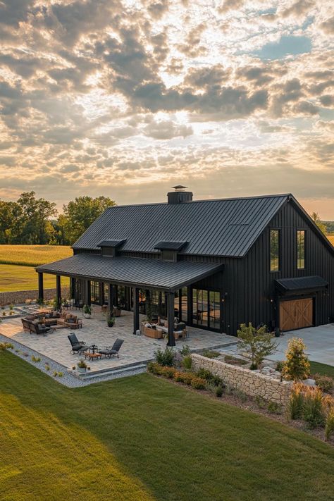 High angle view of a large black shouse barndominium with large side porch large patio and yard stone patio fence large garage doors wide. Unlock the secrets of shouse barndominiums and find out how you can live where the wild west meets modern luxury. Large Property Ideas, Dream Barndominium Ideas, Compound Ideas Home, Barndominium Front Entrance, Barndominium Home Plans, Black Barndominium Exterior With Stone, Shop Next To House, Spanish Barndominium, Charcoal And Black Barndominium